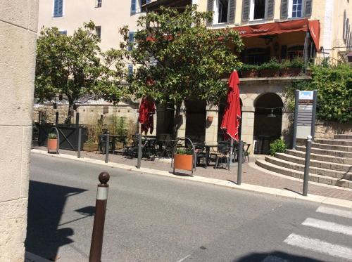 a street with chairs and umbrellas on the side of a building at Hauts de st pierre 3 chambres belle terrasse climatisation in Fayence