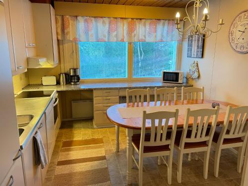 une cuisine avec une table et des chaises ainsi qu'une fenêtre dans l'établissement Omakotitalo 100m2, 3 makuuhuonetta Joensuu, à Joensuu
