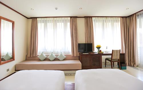 a hotel room with two beds and a desk with a computer at Almanity Hoi An Resort & Spa in Hoi An