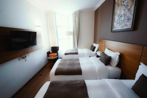 a hotel room with two beds and a flat screen tv at Nour Al Thuria Hotel in Makkah