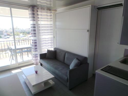 uma sala de estar com um sofá e uma grande janela em le select em Cap d'Agde