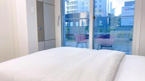 a bedroom with a white bed and a large window at Central City in Incheon