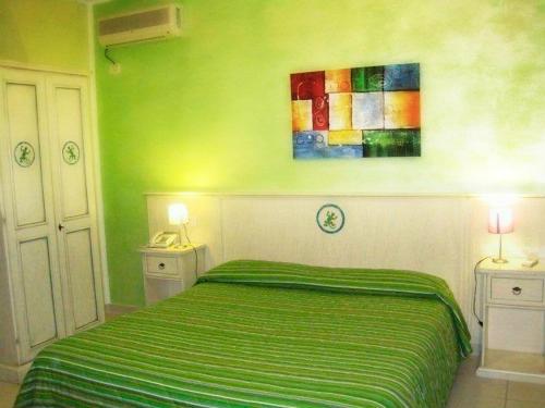 a green bedroom with a bed and a painting on the wall at Hotel Ariadimari in Valledoria