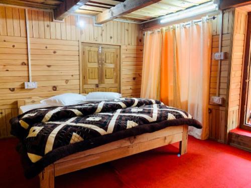 a bedroom with a bed in a wooden room at RRR COTTAGES AND TREE HOUSE BY WB RESORTS in Banjār