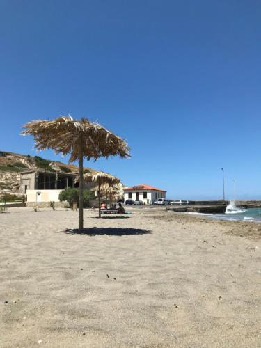 Pachia Ammos的住宿－Country House，沙滩上的草伞和海洋