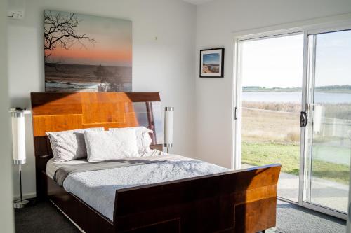 ein Schlafzimmer mit einem Bett und einem großen Fenster in der Unterkunft Coorong Island Retreat - Farm Stay at Pet Friendly Property in Meningie