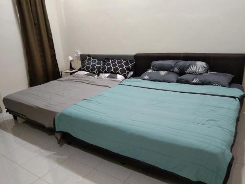 uma cama com um cobertor azul e almofadas em Koolest homestays Meru em Ipoh