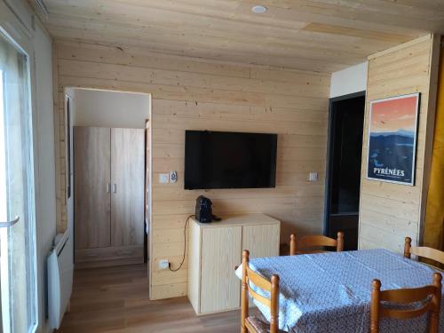 Habitación con mesa y TV en la pared. en Appartement confort et style en pied de piste en Bolquere Pyrenees 2000