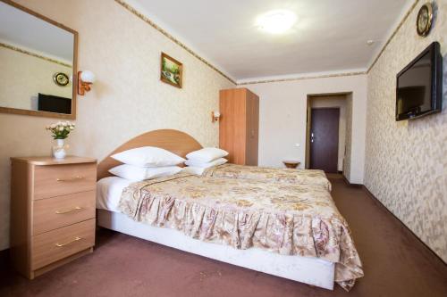 a bedroom with a bed and a dresser and a television at Bukovyna Hotel in Chernivtsi