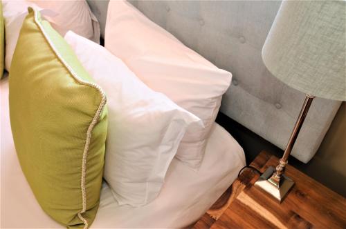 a bed with white pillows and a green pillow at Abbey Manor Luxury Guesthouse in Cape Town