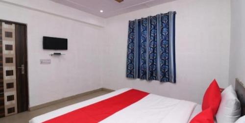 a bedroom with a bed and a tv on the wall at Ganga Guest House By WB Inn in Agra