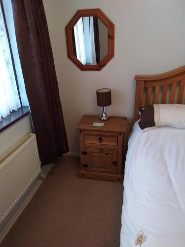 a bedroom with a bed and a table with a mirror at Rose Bungalow In Carlton Colville in Pakefield