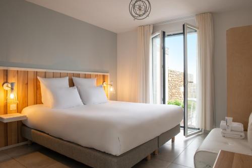 a bedroom with a large bed and a large window at Hôtel Sport & Spa, Ile d'Ouessant, The Originals Collection in Lampaul