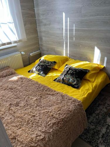 a yellow bed with two black pillows on it at Apartment centru Chisinau in Chişinău