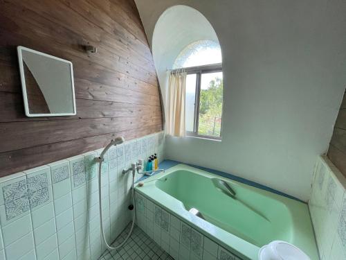 a bathroom with a green tub and a window at Seiryukyou in Nishinoomote