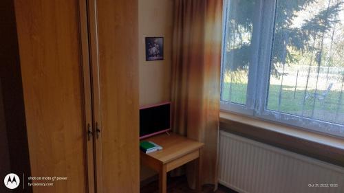 a desk with a computer on it next to a window at Gospodarstwo Agroturystyczne Agroletnica in Świdnica