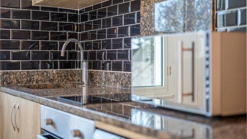 a kitchen with a sink and black tiles on the wall at Esprit cosy - Welc'Home in Limoges