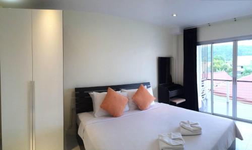 a bedroom with a large white bed with orange pillows at Glitter House Phuket in Kata Beach
