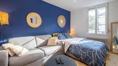 a living room with a couch and a blue wall at Esprit cosy - Welc'Home in Limoges