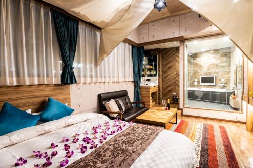 a bedroom with a large bed and a chair at Hotel Bali An Resort Shinjuku Forest in Tokyo
