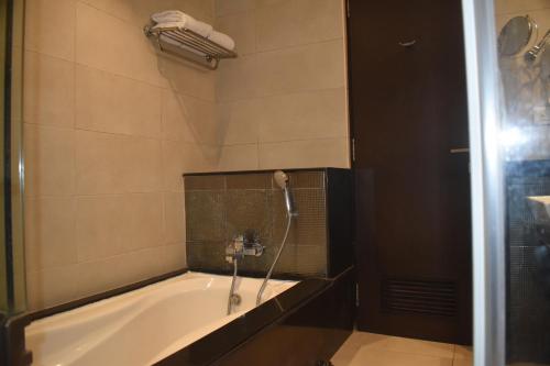 a bath tub with a shower in a bathroom at Royal Orchid Central, Shimoga in Shimoga