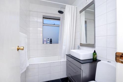 een witte badkamer met een wastafel en een bad bij City view, bright & cozy - Free parking (A4) in Reykjavík