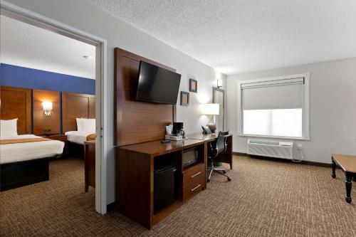 a hotel room with a bed and a desk with a television at Comfort Inn & Suites St Louis-Hazelwood in Hazelwood