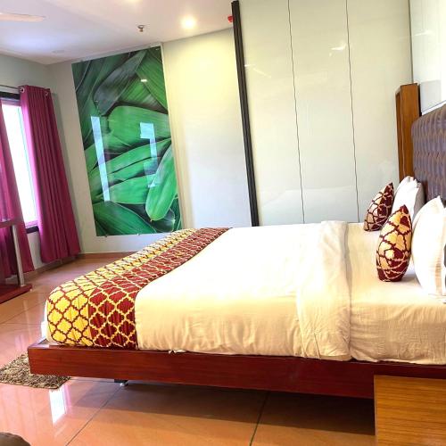 a bedroom with a bed with a large painting on the wall at HOTEL AIRPORT KK in Nagpur