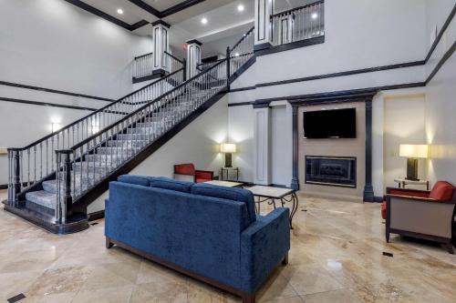 a living room with a blue couch and a staircase at Quality Inn & Suites I-35 E/Walnut Hill in Dallas