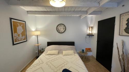 a bedroom with a bed and a clock on the wall at Joli mazet à Nîmes idéalement situé entre la garrigue et la ville in Nîmes