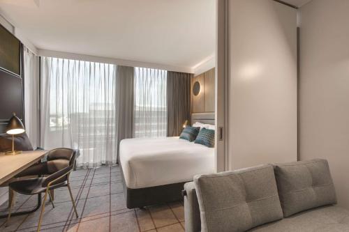 a hotel room with a bed and a desk and a chair at Vibe Hotel Sydney Darling Harbour in Sydney