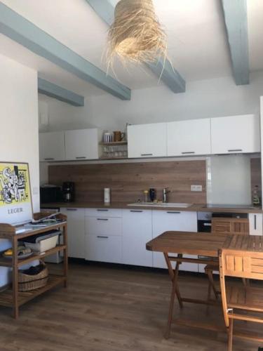 une cuisine avec des armoires blanches et une table en bois dans l'établissement Logement entier - Quartier Phare - Tranche sur Mer, à La Tranche-sur-Mer