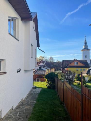 a white house with a fence and a church at Sifra 276 in Nová Lesná