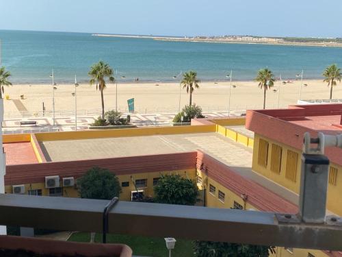 エル・プエルト・デ・サンタマリアにあるApartamento en primera línea de playa con piscina.の黄色の建物とビーチの景色を望む