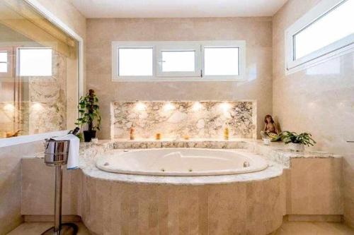 baño grande con bañera grande y 2 ventanas en Gorgeous Villa near Ibiza centre, en Santa Eulària des Riu