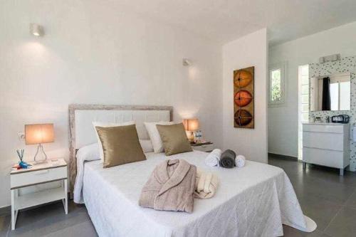 Un dormitorio con una cama blanca con toallas. en Gorgeous Villa near Ibiza centre, en Santa Eulària des Riu