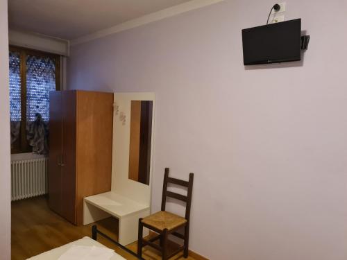 Pokój z krzesłem i telewizorem na ścianie w obiekcie NEW NAPOLEONICO w mieście Bondeno