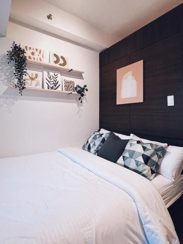 a bedroom with a white bed and a black wall at Rustic industrial 1-BR condo with balcony at Air Residences Makati Manila in Manila