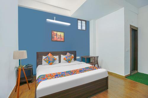 a bedroom with a large bed with a blue wall at FabExpress Saket Inn in Bhopal