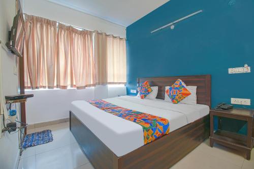 a bedroom with a bed with a blue wall at FabExpress Saket Inn in Bhopal