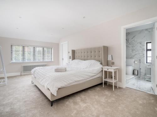 ein weißes Schlafzimmer mit einem großen Bett und einem Spiegel in der Unterkunft Pass the Keys Luxury 4 Bedroom home with large garden in Watford