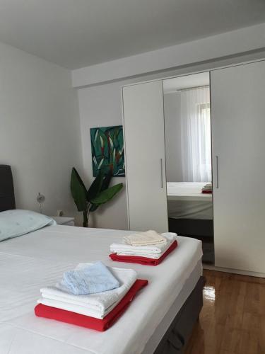 ein Schlafzimmer mit einem weißen Bett und Handtüchern darauf in der Unterkunft Apartmani Nada in Novalja