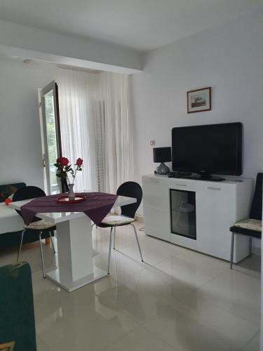 a living room with a television and a table and chairs at Apartmani Nada in Novalja