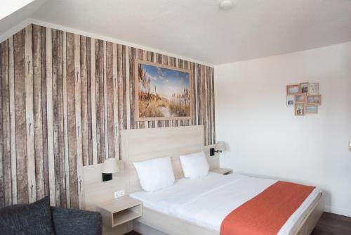 a bedroom with a bed and a painting on the wall at Hotel Up´n Diek in Dangast