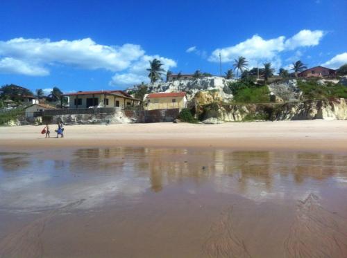 a beach with people walking on the sand and houses at Beach Place Fontainha in Aracati