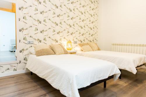 2 camas en una habitación con pájaros en la pared en Moderno Apartamento LAUD3 - Nuevo/Familiar/Wifi/TV, en Valladolid