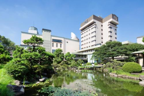 un jardin en face des bâtiments avec une rivière dans l'établissement Art Hotel Kokura New Tagawa, à Kitakyūshū