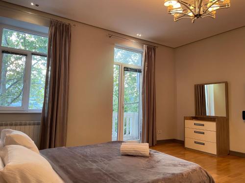 a bedroom with a bed and a mirror and windows at Central Park apartment in Baku