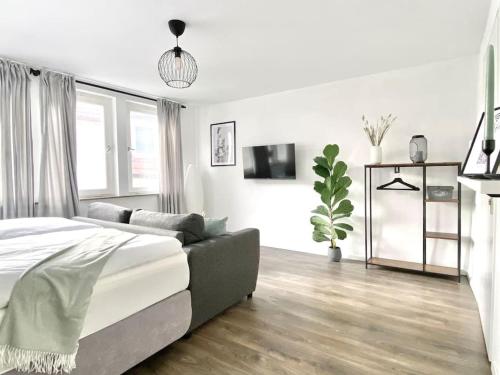 a white bedroom with a bed and a couch at City-Apartment No 2 in Reutlingen