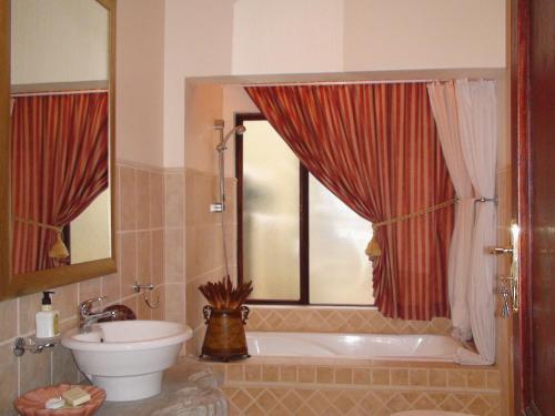 a bathroom with a tub and a toilet and a sink at Villa Lugano Guesthouse in Johannesburg